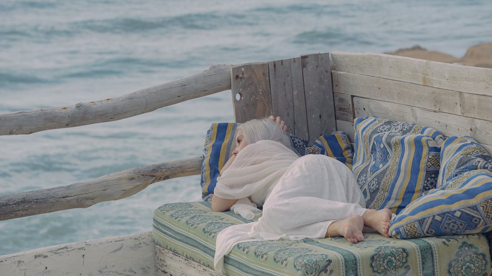 Guest resting on a daybed with Moroccan cushions above the ocean
