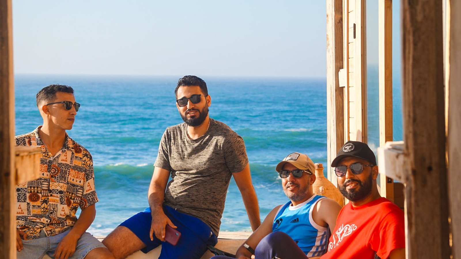 Friends sitting on the Ajarif terrace with the blue ocean behind
