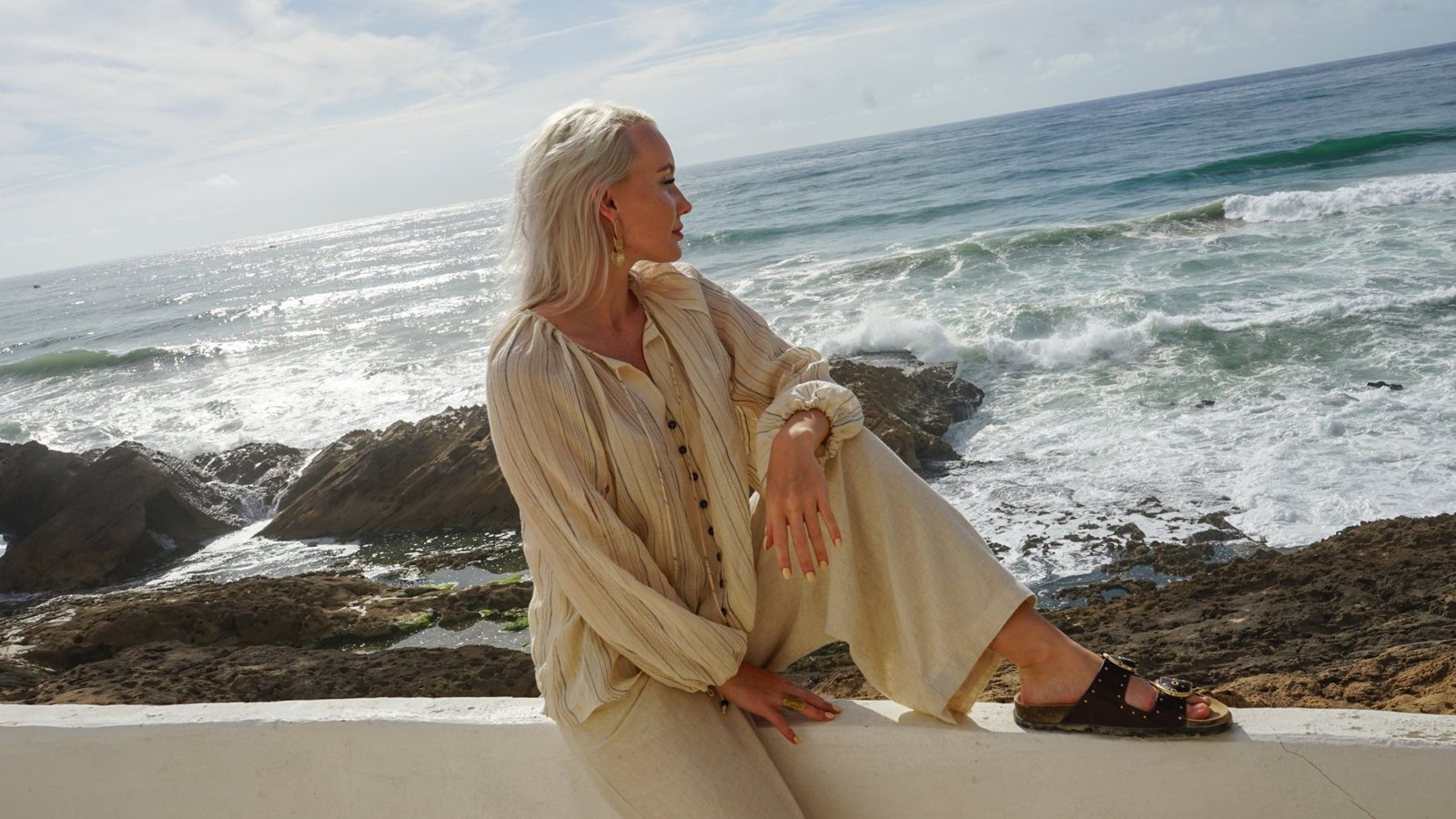 Guest sitting on the sea wall at Ajarif with waves on the rocks