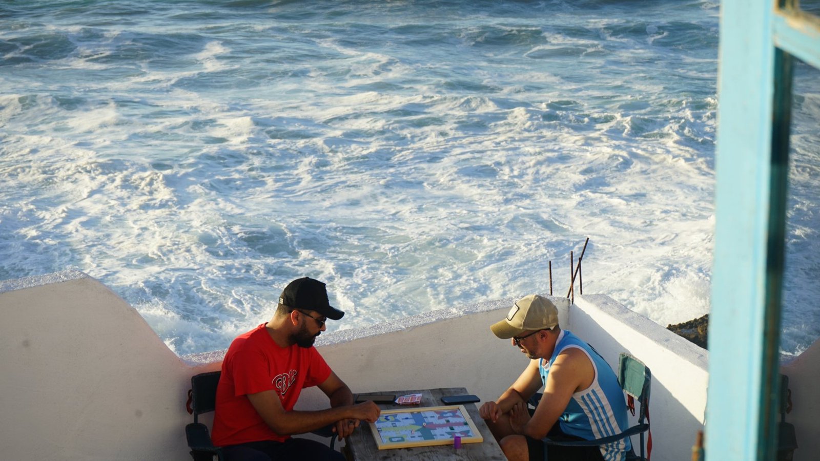 Two guests playing a board game on the terrace above the waves