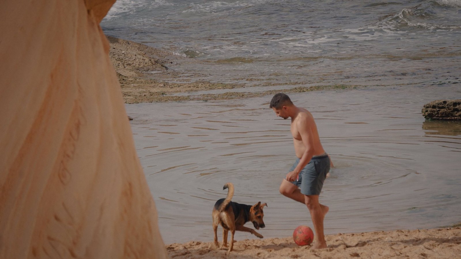 Playing football with a dog on the beach by the rock pools in Timlalin
